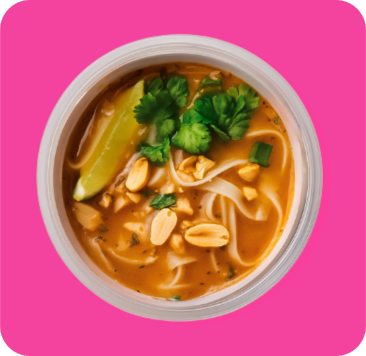 Noodle soup with peanuts, green onions, and a lime wedge in a white bowl.