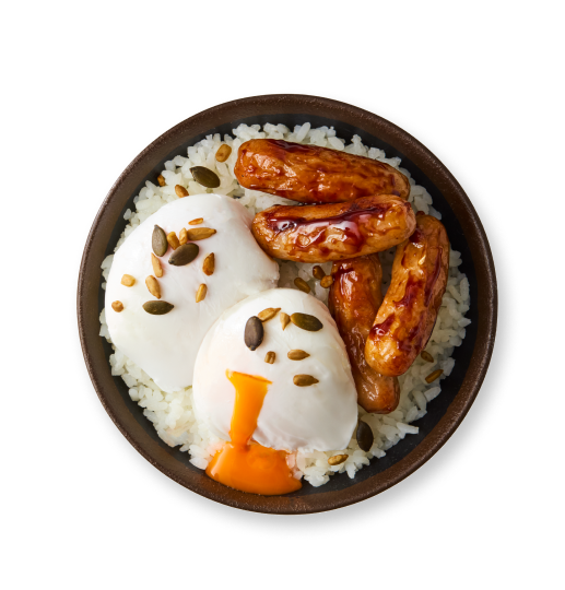 Two poached eggs with nuts, grilled sausages, and white rice in a dark bowl.