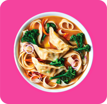 Bowl of noodle soup with dumplings, broccoli, carrots, and red onions.