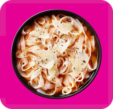 Bowl of flat pasta with shaved parmesan cheese and fresh black pepper.