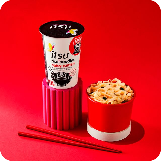 Itsu Spicy Ramen cup with prepared noodles in a red bowl and chopsticks.