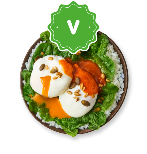 Vegetarian bowl with poached eggs, orange sauce, pumpkin seeds, rice, and fresh greens.