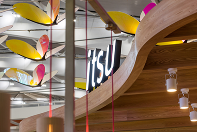 itsu restaurant sign with colorful leaf-shaped lights and curved wooden details.