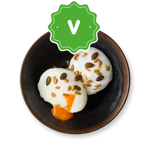 Two perfectly poached eggs with runny yolks, topped with various seeds in a dark bowl.