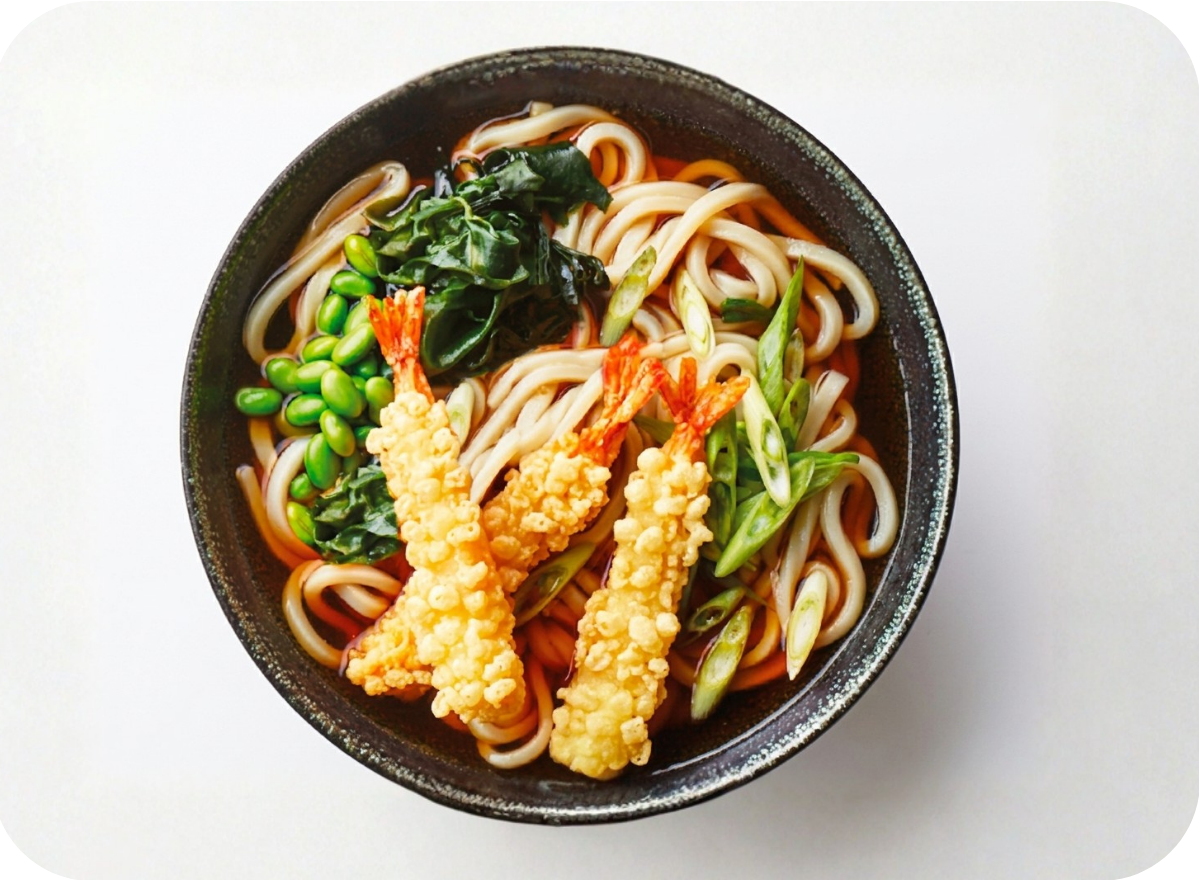 Japanese udon noodle soup with shrimp tempura, green onions, edamame, and wakame.