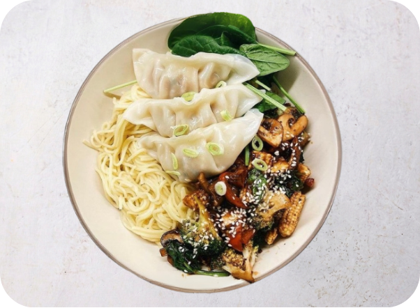 A bowl of Asian-inspired noodles, dumplings, and a savory vegetable stir-fry.