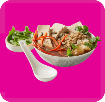 Hearty soup with tofu, shredded carrots, pumpkin seeds, and minced meat served with a spoon.