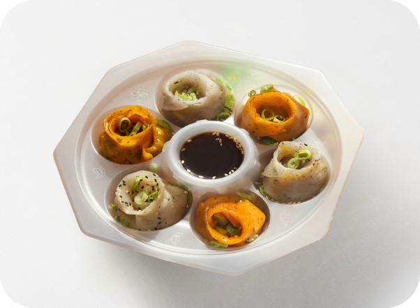 Assorted steamed dumplings with green onions and soy dipping sauce in a hexagonal container.